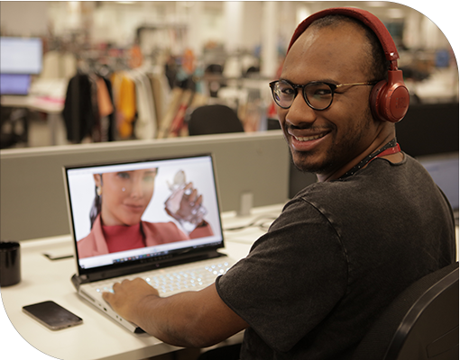 Jovem rapaz negro sentado à mesa e ao computador em ambiente corporativo